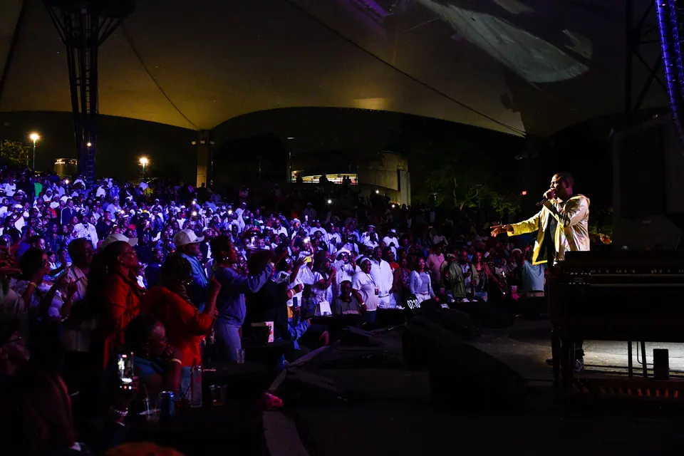 A performer faces a packed house under the canopy of the Aretha Franklin Amphitheatre during a J3 Productions concert in Detroit