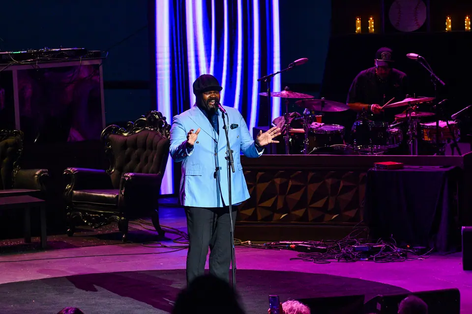 Gregory Porter on stage with his band at dusk, the Detroit River behind him
